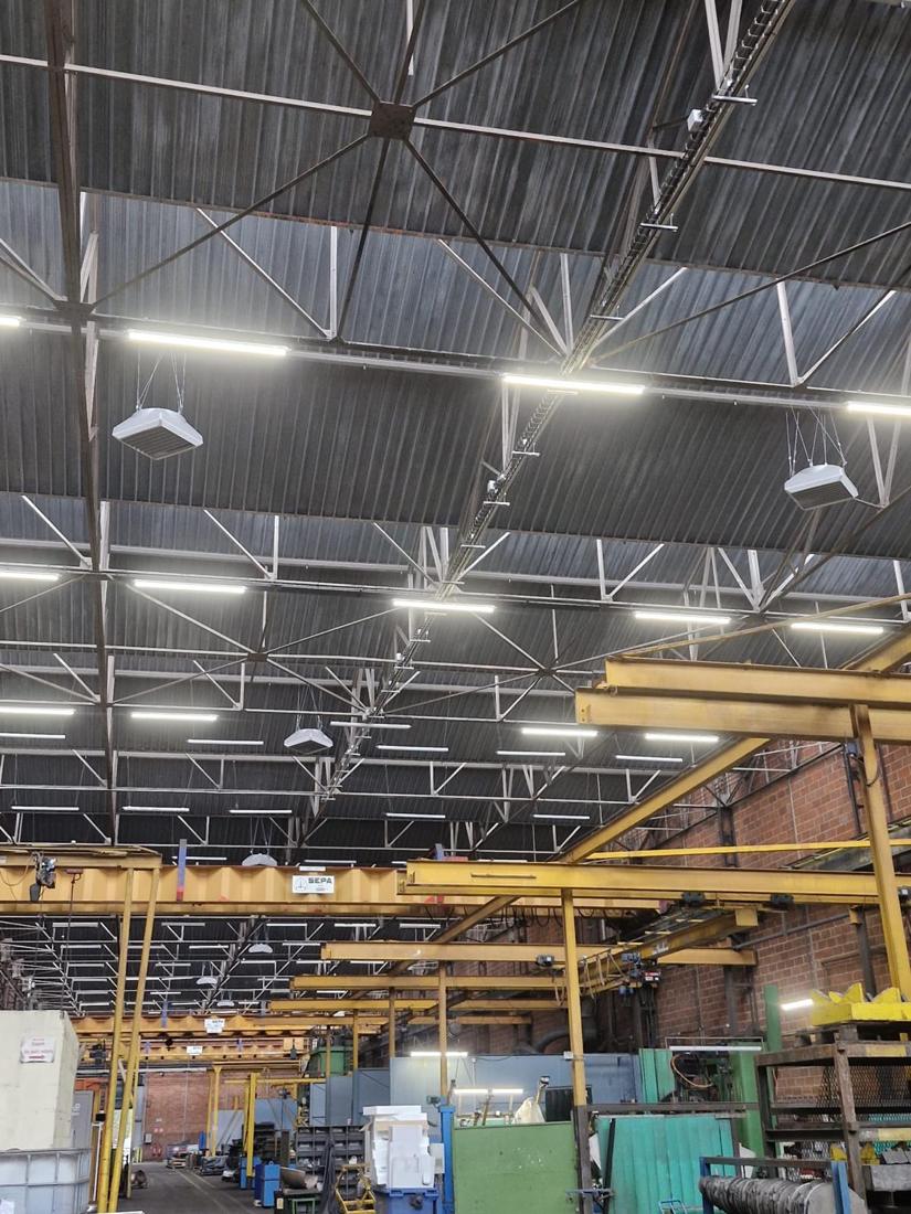 Hall industriel : Déstratificateurs suspendus sous la toiture, au-dessus des ponts roulants.